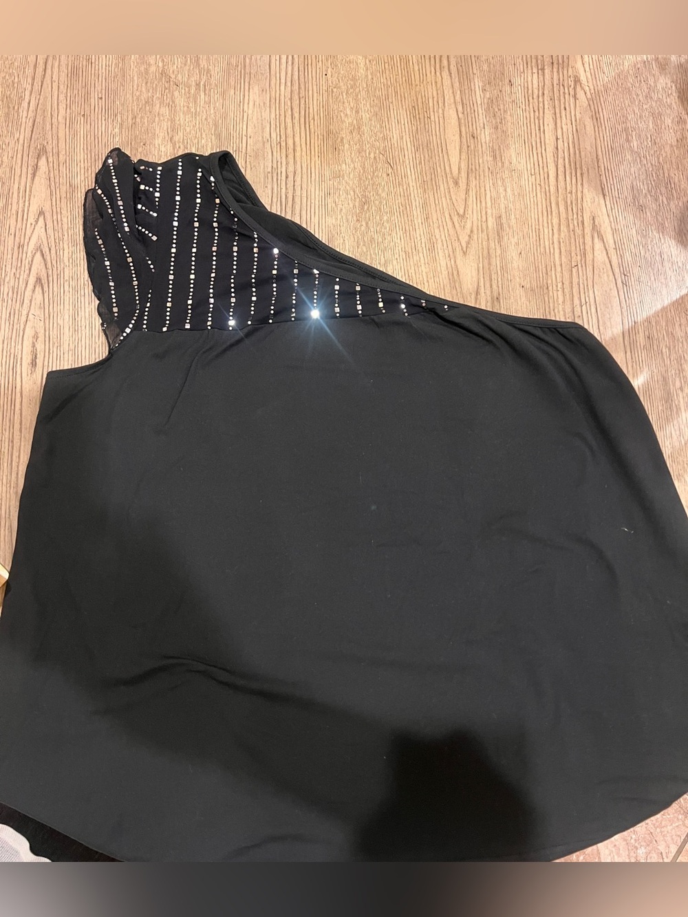 Black one-shoulder blouse with rhinestone mesh detail.